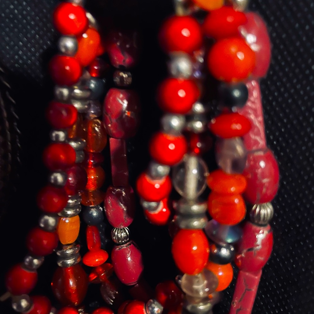 Boho styled wrist beaded bracelet in rich red tones and silver metal pieces.